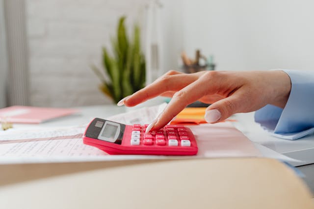 person putting numbers into a pink calculator